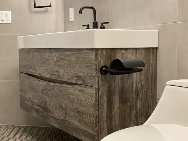 Floating weathered-wood bathroom vanity with a white integrated sink, matte black faucet and black towel bar