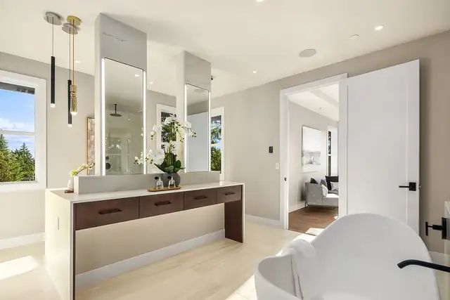 Bathroom with a wood-front vanity, tall mirrors, pendant lights and a freestanding tub