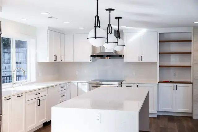 White kitchen remodel on the Eastside with a quartz waterfall island, open wood shelves and black-and-glass pendant lights